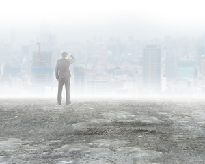 Man standing and gazing city buildings in mist