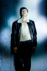 handsome young man in black jacket posing in studio. Sexy young man with muscular body and bare torso