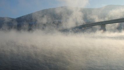 The bridge over the river in a thick fog