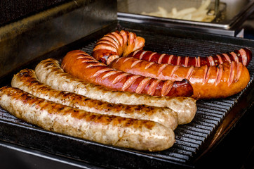 assorted sausages grilled on skewers on a large plate, mushrooms on the grill. Street festival food. © mykytivoandr