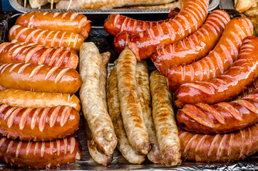 assorted sausages grilled on skewers on a large plate, mushrooms on the grill. Street festival food.