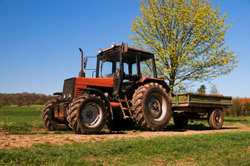 Old rusty tractor with a trolley on a spring field in Germany