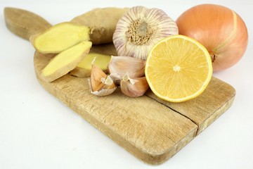 Natural treatment. Closeup of a wooden board placed garlic, ginger, lemon, onion. Natural medicine for flu, bronchitis and colds. Wooden board resting on a white background. Isolated.