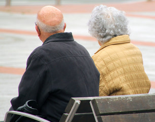 Pareja de ancianos sentado en un banco en la calle