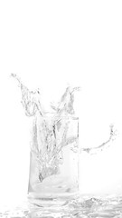 Ice cubes splashing into glass of water isolated on white background