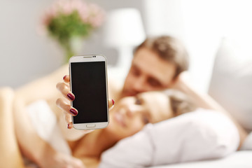 Young couple in bed with smartphone