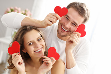 Playful couple with hearts in bedroom