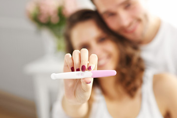 Happy couple with pregnancy test in bedroom © Kalim