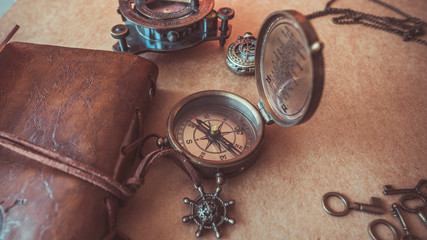 Fototapeta na wymiar Vintage compass and tawny leather wallet on a brown wallpaper background in vintage style.