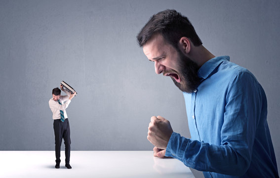 Young businessman fighting with miniature businessman