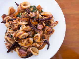 Stir Fried squid with salted egg york, seafood menu (local traditional Thai food) in white plate on wooden table.