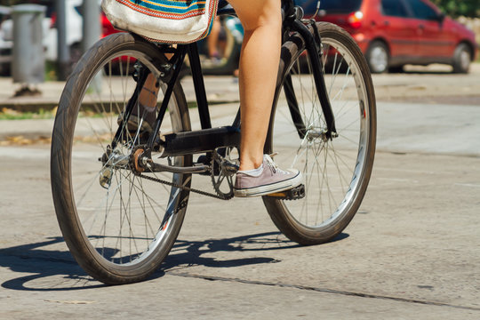 Fototapeta Woman legs riding a bicycle down the street