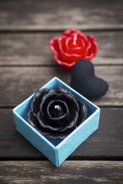 Black rose candle in blue box on old wooden floor, black valentine concept