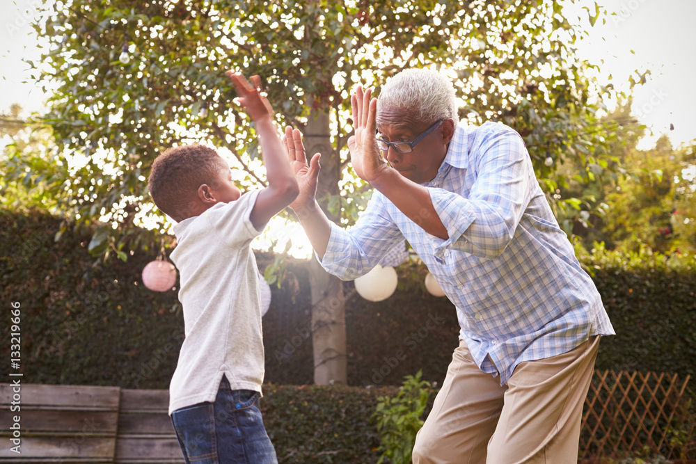 Wall mural black grandfather playing with his grandson in a garden