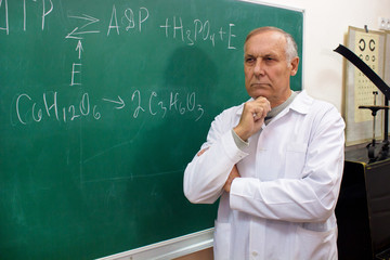Aged professor thinking near the blackboard