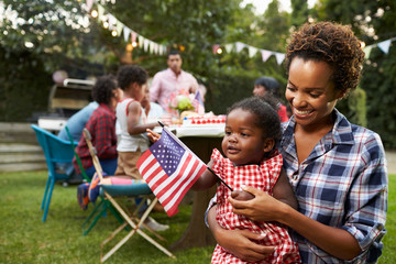 Black mother and baby holding flag at 4th July garden party