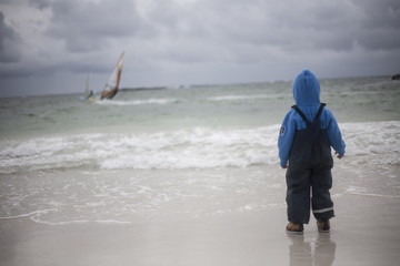 Kid looking at windsurfers