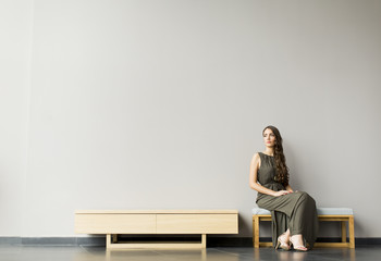 Pretty young woman sitting on bench in the modern room