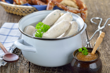 Frische Weißwürste im Topf mit Brezen und süßem Senf serviert - Hot Bavarian white sausages in...