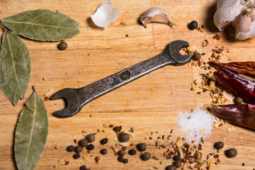 Spices on the kitchen board and a wrench.