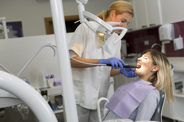 Doctor in uniform checking up female patient's teeth in dental c
