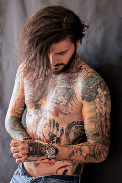 Tattooed naked man with messy wet hair checking his watch