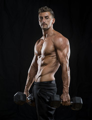 Mature athlete holding dumbells weights with black background  
