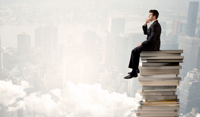 Student in city sitting on stack of books