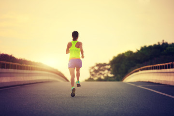 young fitness asian woman runner running on city road