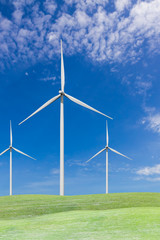 Fototapeta premium Wind turbines on grass field and blue sky