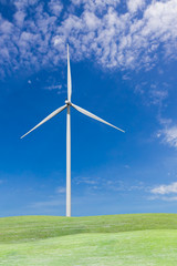 Fototapeta premium Wind turbine on grass field and blue sky