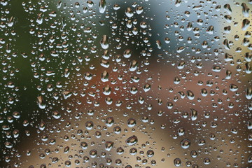 Rain drops on window with house and church in background