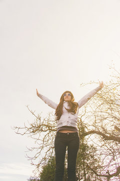 Mujer joven y feliz con sus brazos hacia el cielo y la luz del atardecer 