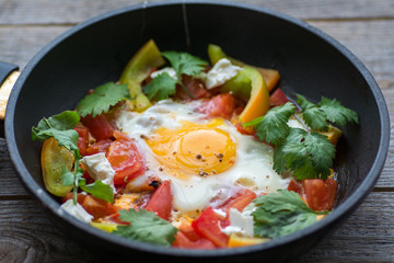 fried egg in a pan with tomatoes and greens