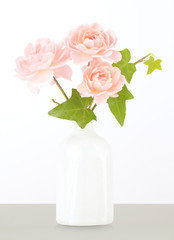 Pastel pink garden roses in white vase