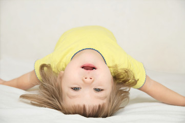 happy funny little girl arched back lying on bed isolated, hap
