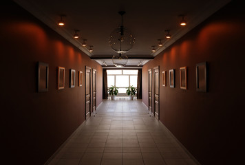 Interior of a dark hotel corridor. Long empty hallway, light in the end