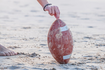 Close up of hand over from rugby ball on the beach. Hand of football player making touchdown. Sport...