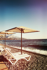 Sunshades and chaise lounges on beach. Summer seascape.