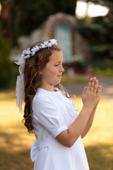Śliczna dziewczynka ma złożone dłonie w czasie modlitwy.