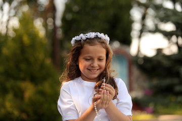 Fototapeta Radosna dziewczynka z różańcem w dłoniach. obraz