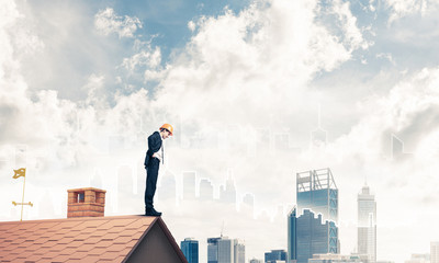 Engineer man standing on roof and looking down. Mixed media