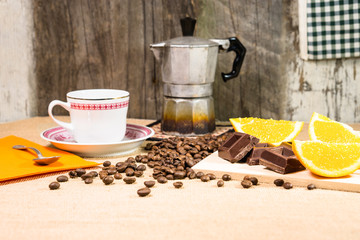 Rustic breakfast table with chocolate bar coffee beans mocha and sliced orange - View of vintage style kitchen with natural energy giving food on old wooden background - Concept of retro lifestyle