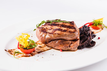 Grilled pork with prunes on an oval white plate close