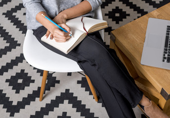 Cropped shot of young businesswoman writing notes, outsource concept