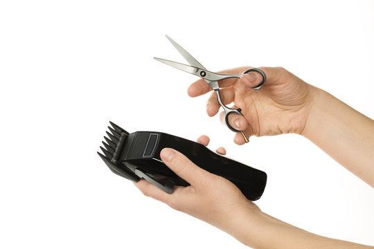 Closeup image of hands holding hair clipper and scissor, isolated on white background