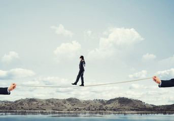 Business concept of risk support and assistance with man balancing on rope