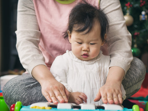 Asian Baby girl playing piano toy with Mom