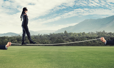 Business concept of risk support and assistance with man balancing on rope