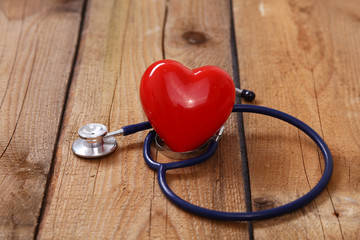 Heart with a stethoscope, isolated on wooden background